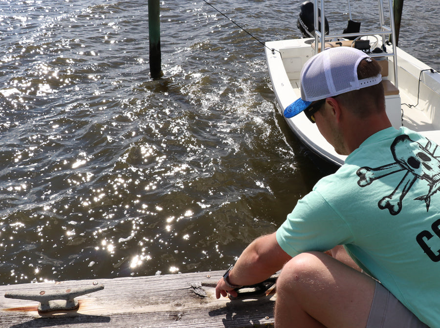 Fisherman wearing Calcutta Outdoors shirt while adjusting dock lines