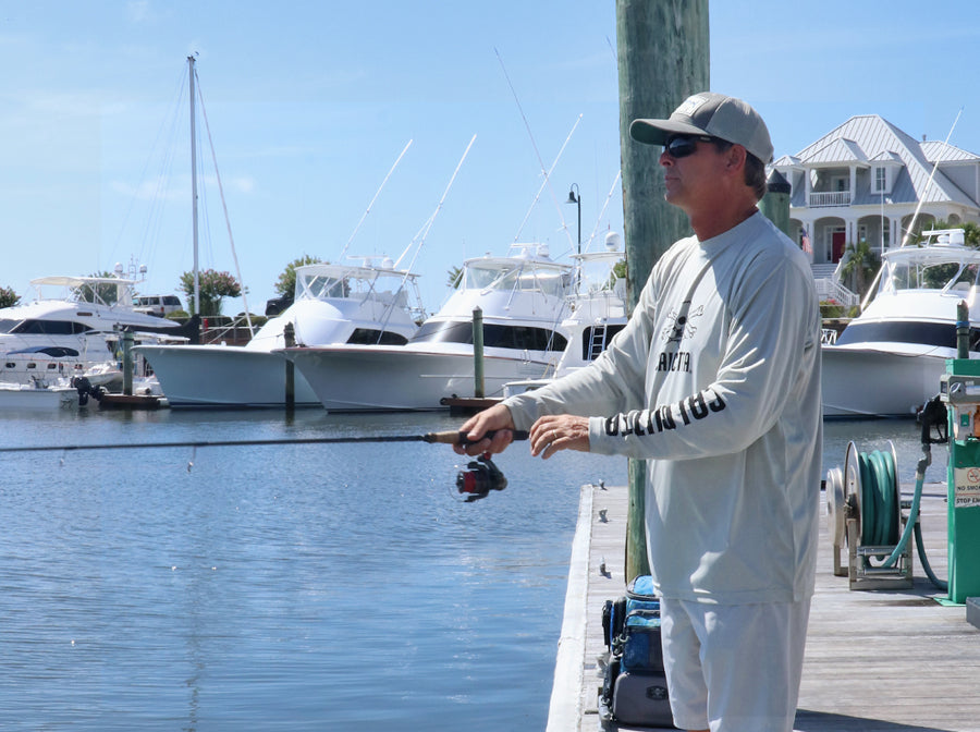 Fisherman wearing Calcutta Outdoors Performance Shirt while fishing from dock