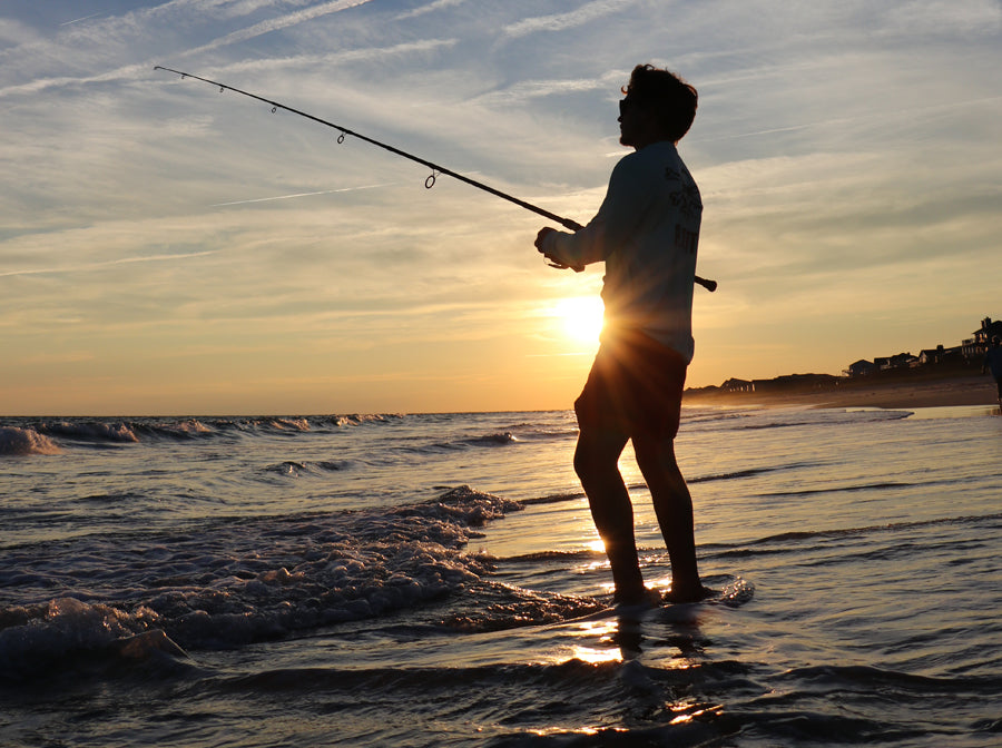 Fisherman surf fishing at sunset